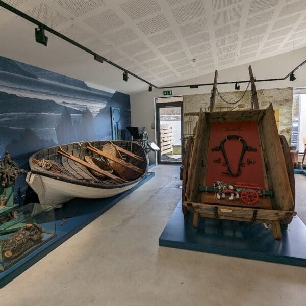 Strathnaver Museum exhibits showing a rowing boat and a horse drawn cart.