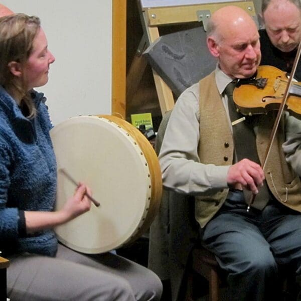 Two people playing instruments, drum and fiddle, in the Castletown Heritage Centre