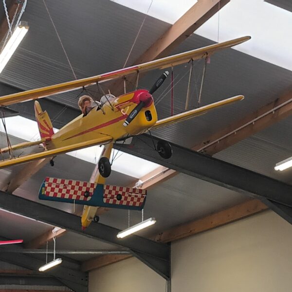 A model plane hanging from the ceiling with a pilot in the cockpit, in the Halkirk heritage & Motor Society