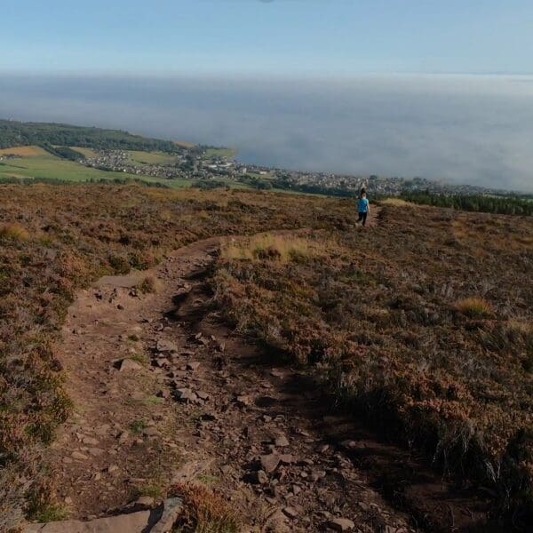 People walking down Ben Bhraggie, the view shoes the downward slope along with the sea and Golspie in the distance, near the North Coast 500
