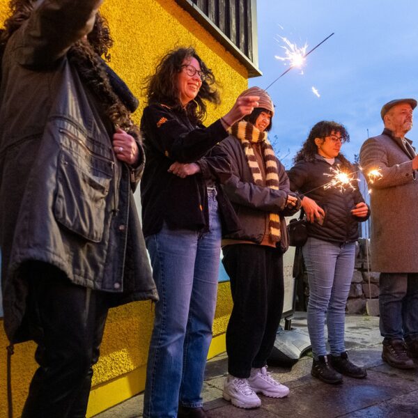 A crowd of people holding sparklers in the evening, at Timepsan, Helmsdale.