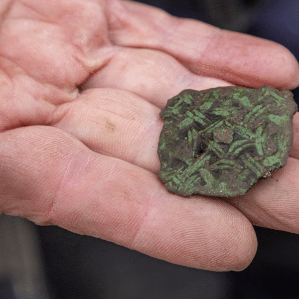 A man holding a small carved metal object found from Nybster Broch