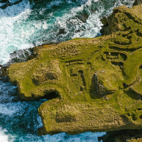 Aerial view of Nybster Broch, with the waves crashing against the cliff, near the North Coast 500